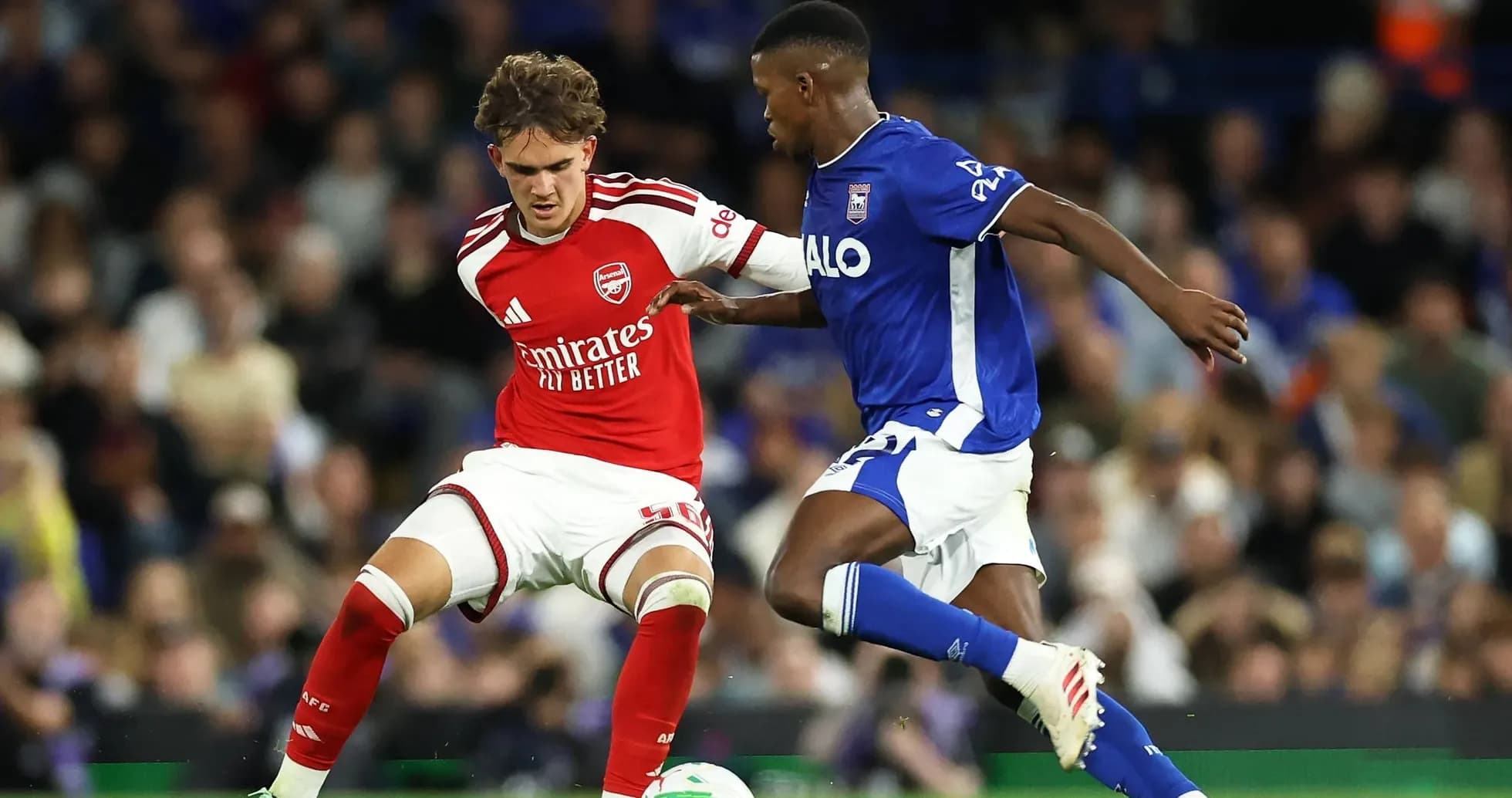 Arsenal player challenges Ipswich Town player for the ball