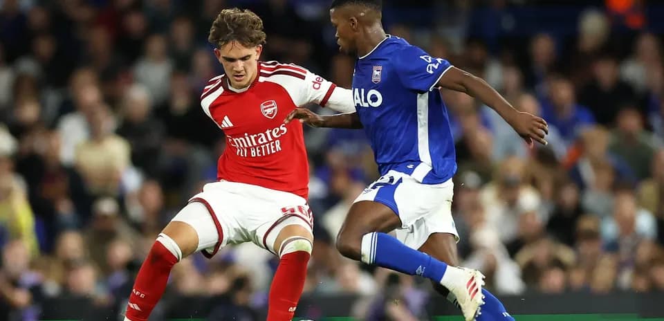 Arsenal player challenges Ipswich Town player for the ball