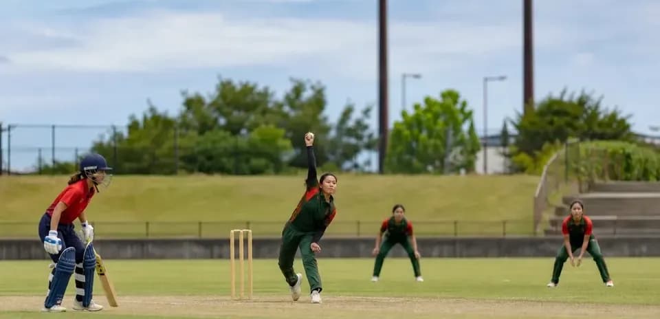 Bowler delivering ball with fielders positioned