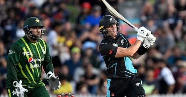 Batsman hitting ball with bowler watching