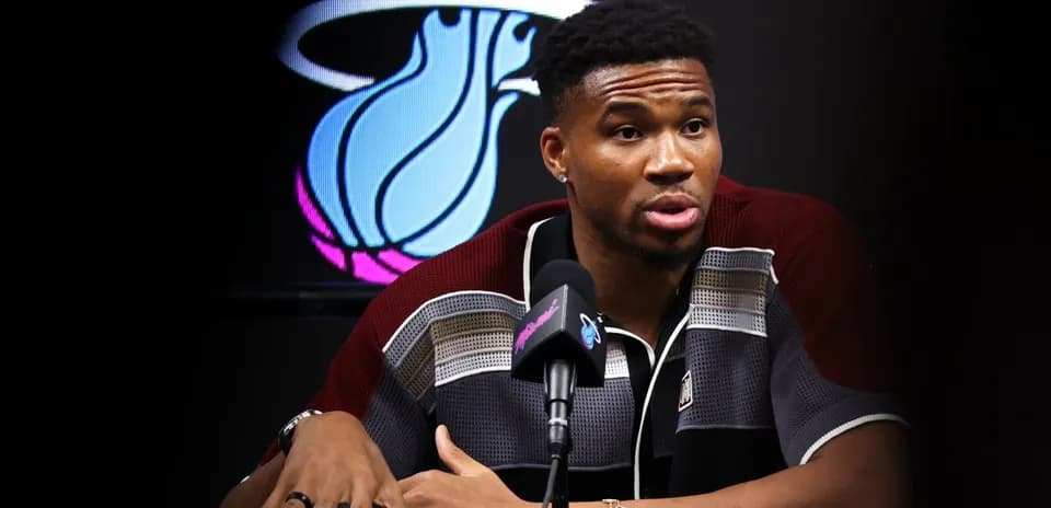 Player speaking at press conference with team logo behind