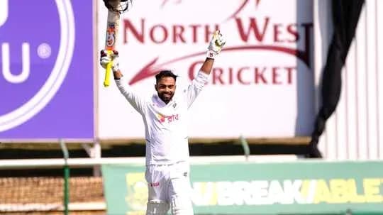 Batsman celebrating century with raised bat on field