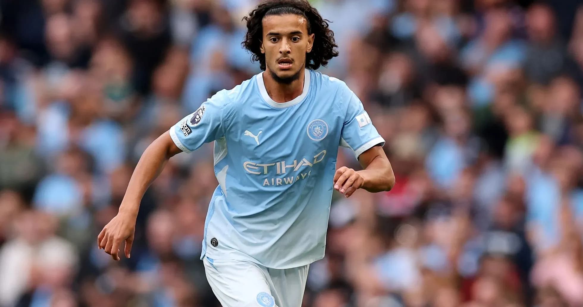 Player running on pitch in Manchester City kit