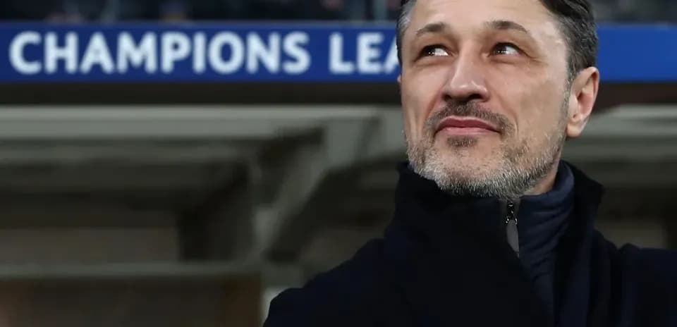 Coach observing match with Champions League banner above