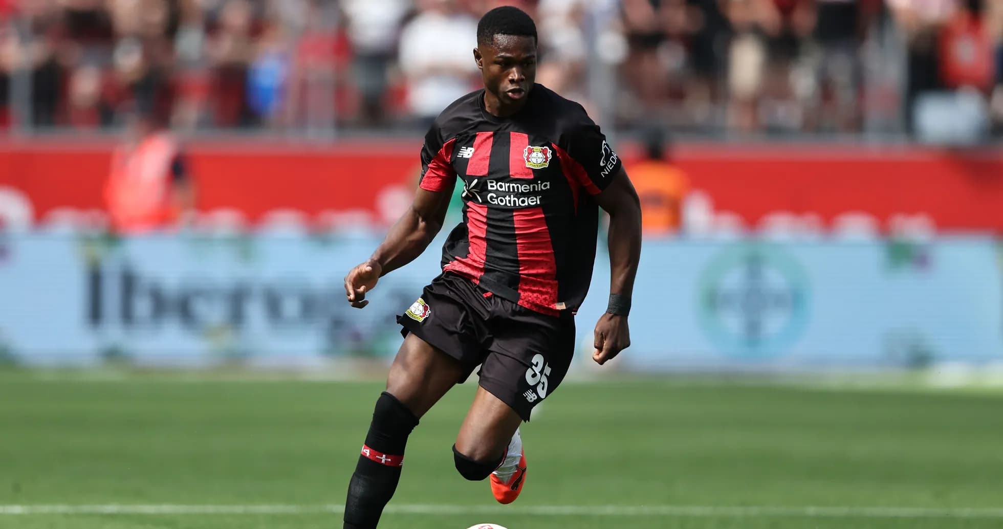 Player in Bayer Leverkusen kit dribbling the ball