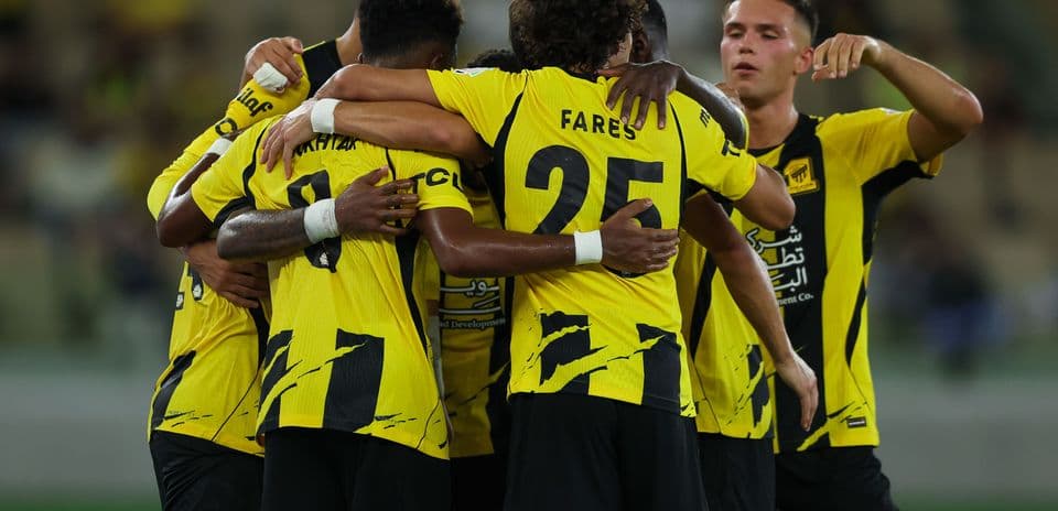 Players celebrating a goal in team uniforms