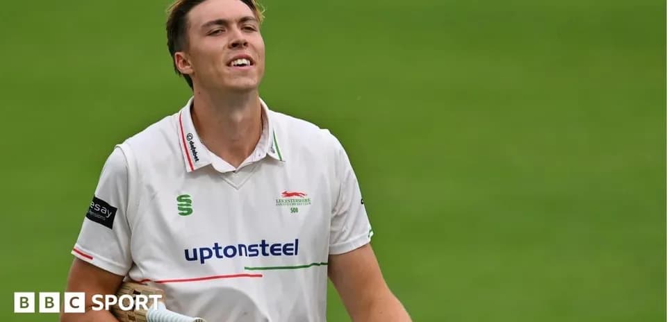 Cricketer walking off field with bat in hand