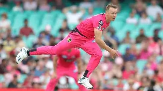 Bowler delivering ball in pink cricket uniform