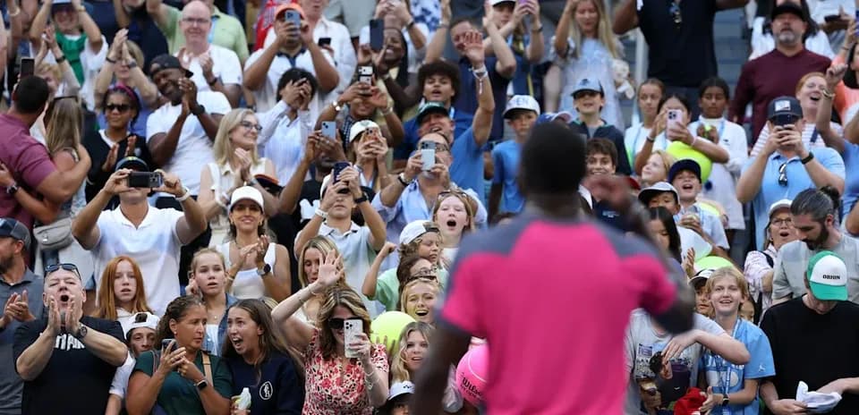 Crowd cheering and taking photos at tennis event