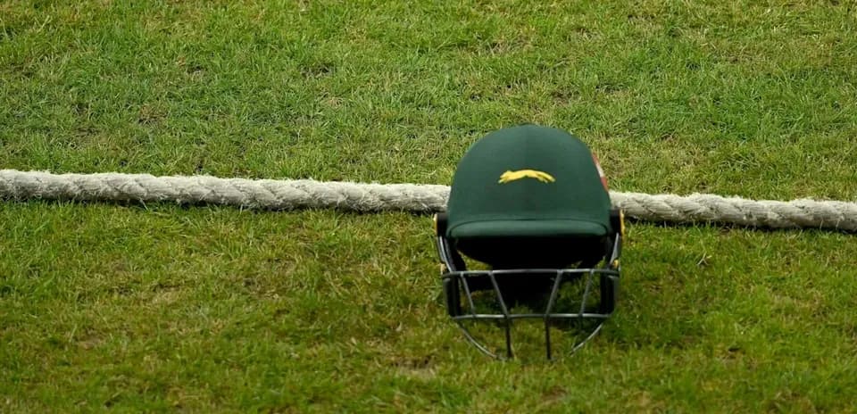 Cricket helmet resting on grass near rope