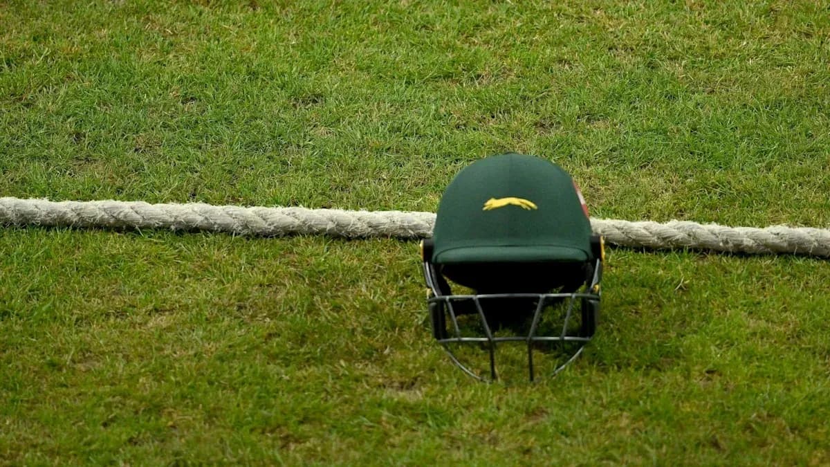 Cricket helmet resting on grass near rope