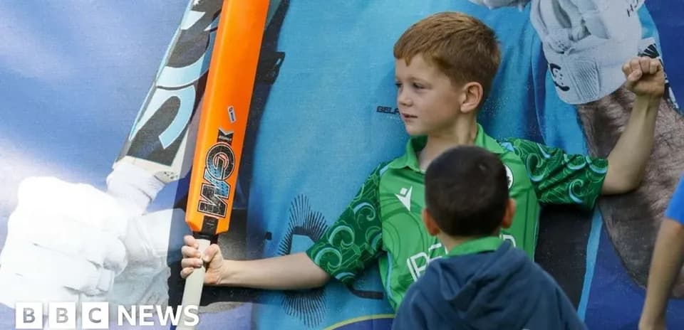 Boy holding a cricket bat beside a poster