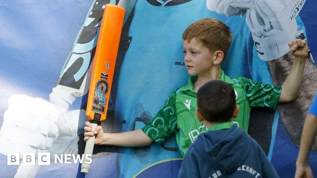 Boy holding a cricket bat beside a poster