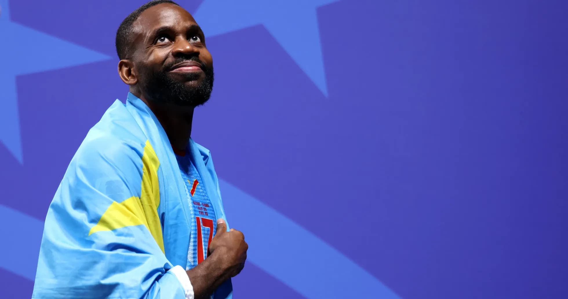 Athlete wearing a flag at an event backdrop
