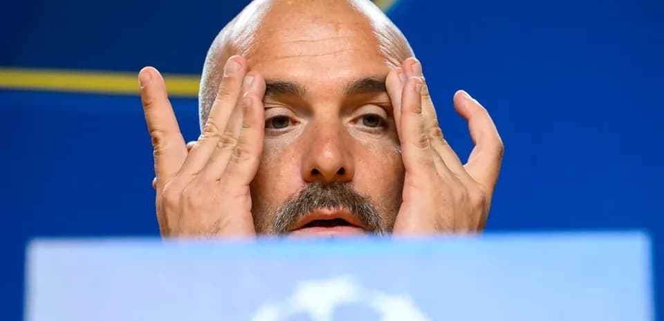 Coach at press conference with hands on face