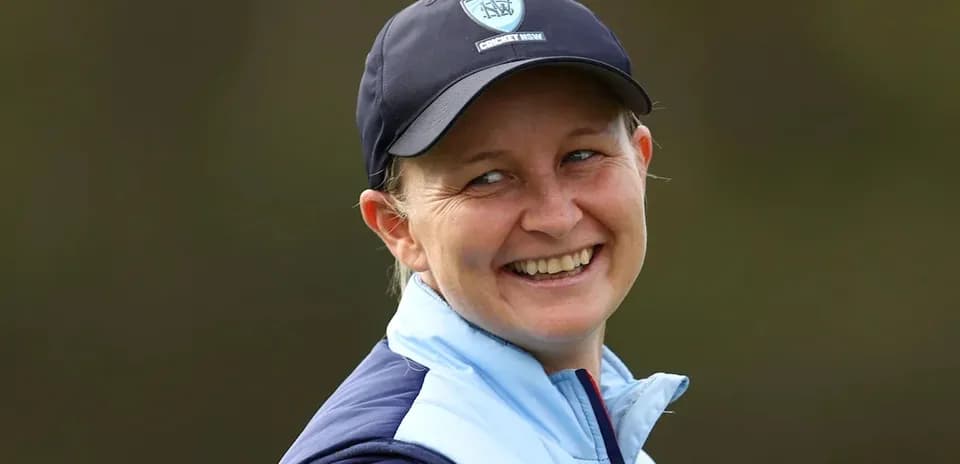 Smiling woman wearing cricket cap and jacket