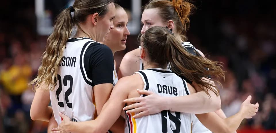 Four basketball players celebrating together on court