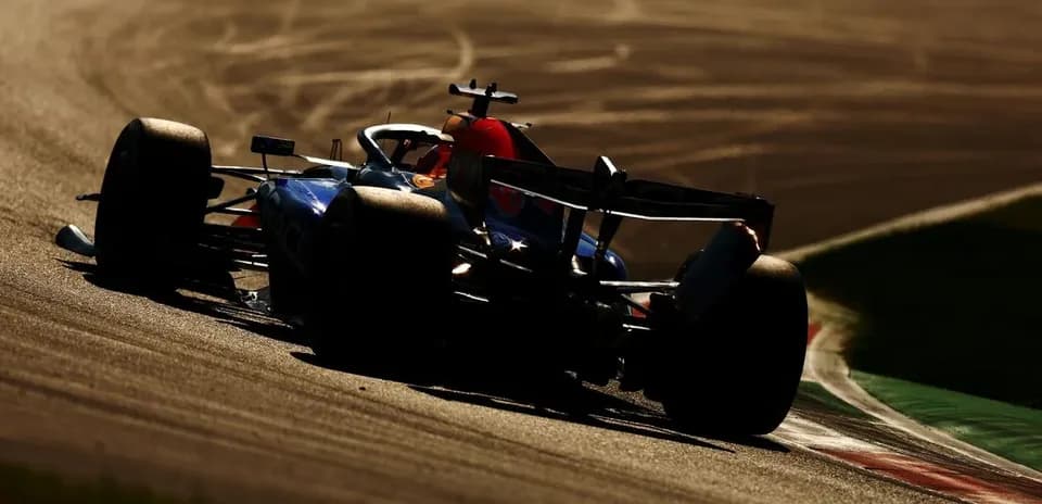 Formula 1 car driving on track during sunset