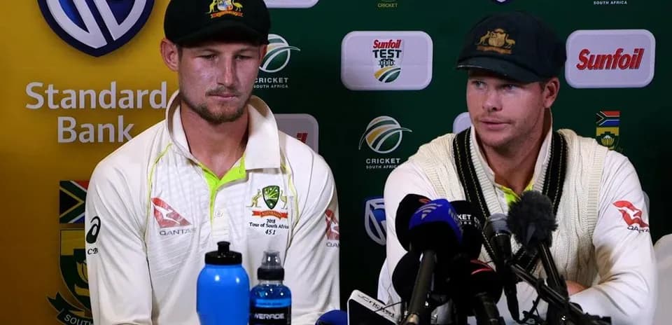 Two cricketers at press conference with microphones