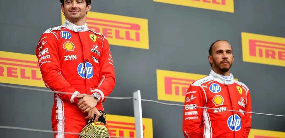 Two drivers on podium wearing Ferrari race suits