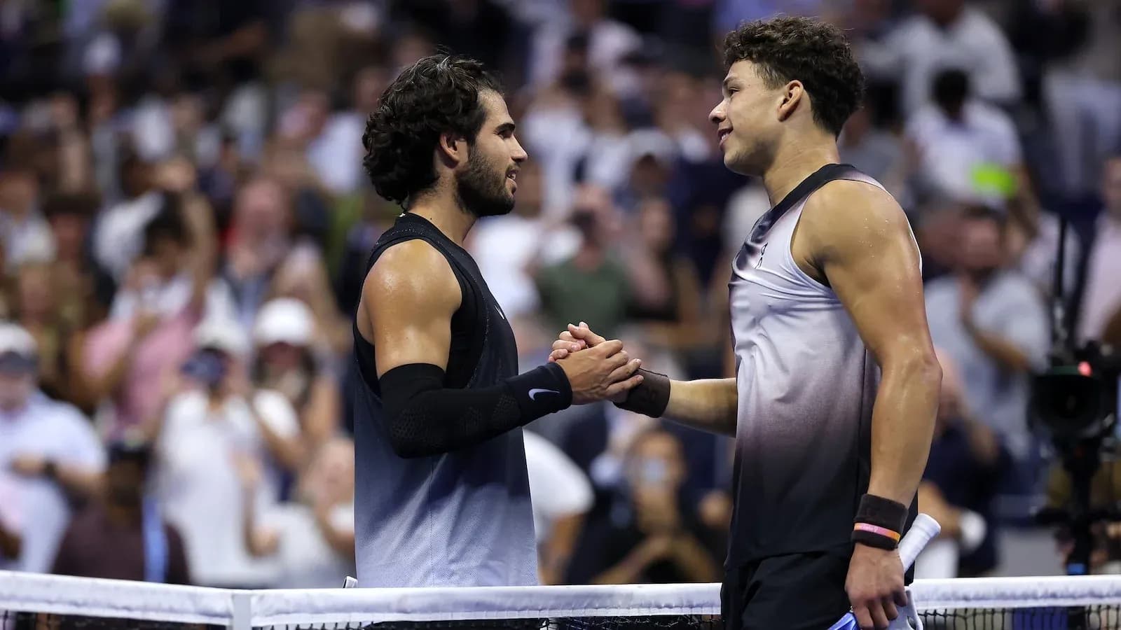 Two tennis players shaking hands at net