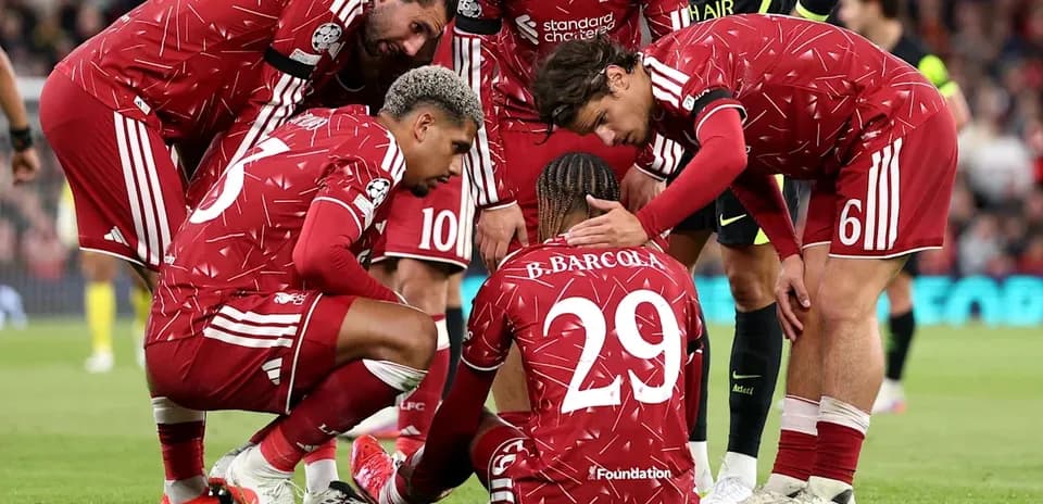 Liverpool players surrounding teammate on the ground