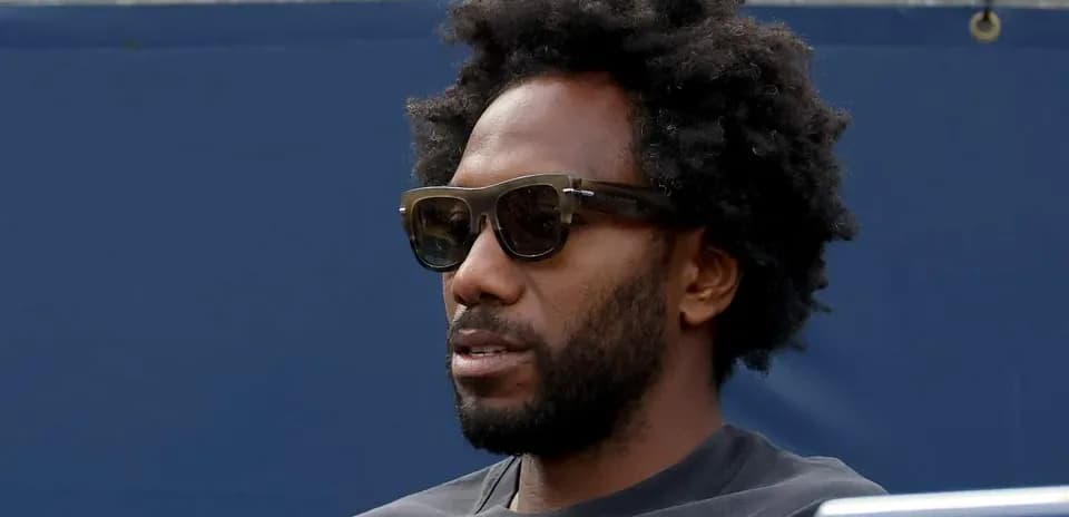 Man wearing sunglasses sitting at event