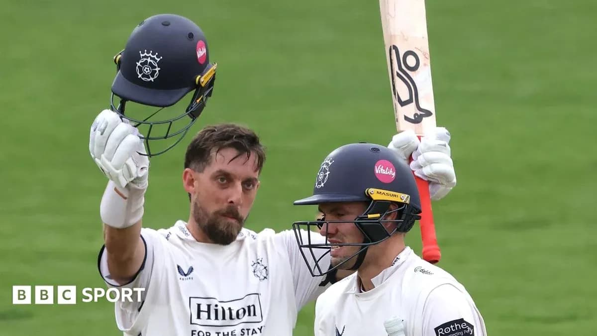 Two cricketers celebrating a milestone with helmets raised