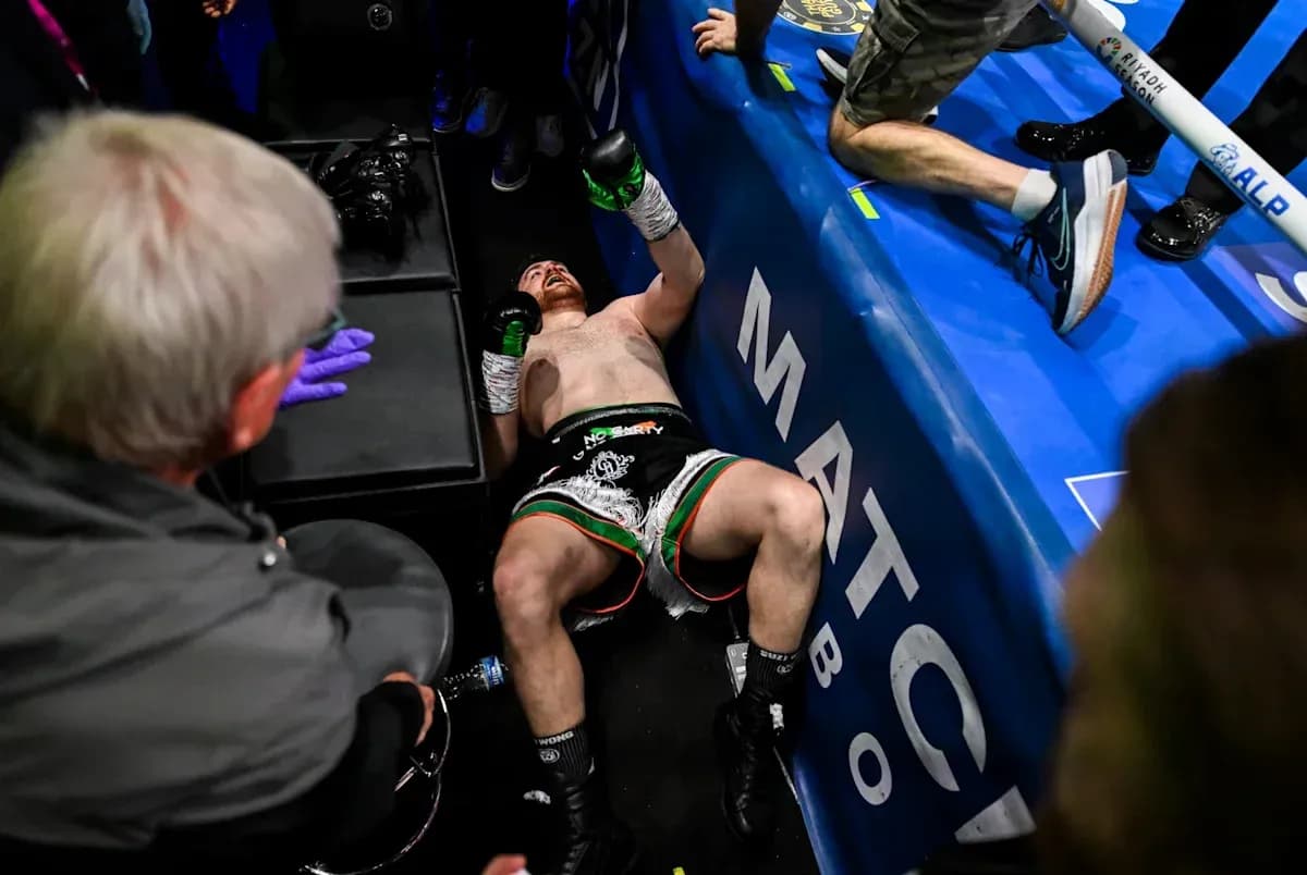 Boxer on the floor after match, surrounded by people
