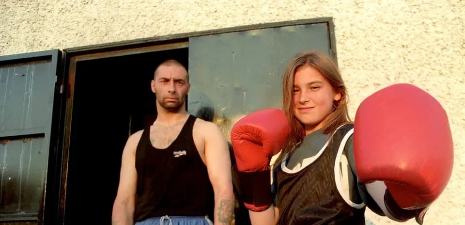 Young female boxer posing with gloves and trainer