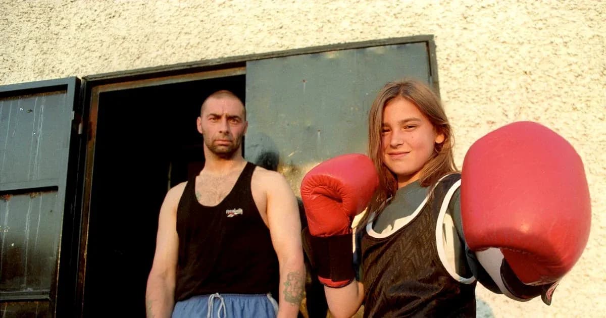 Young female boxer posing with gloves and trainer