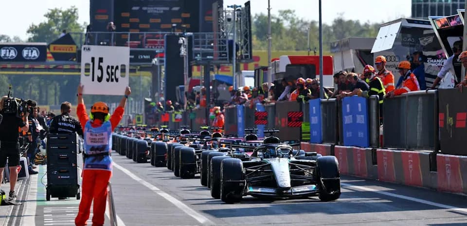 Cars lined up in pit lane with time penalty sign
