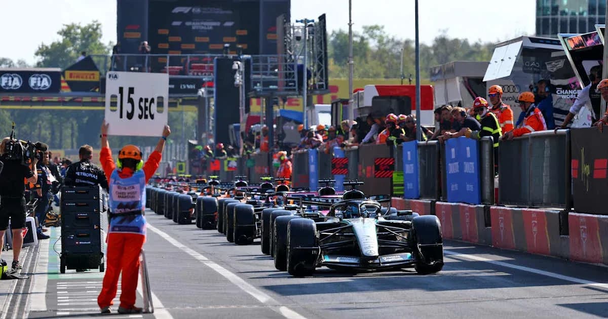 Cars lined up in pit lane with time penalty sign