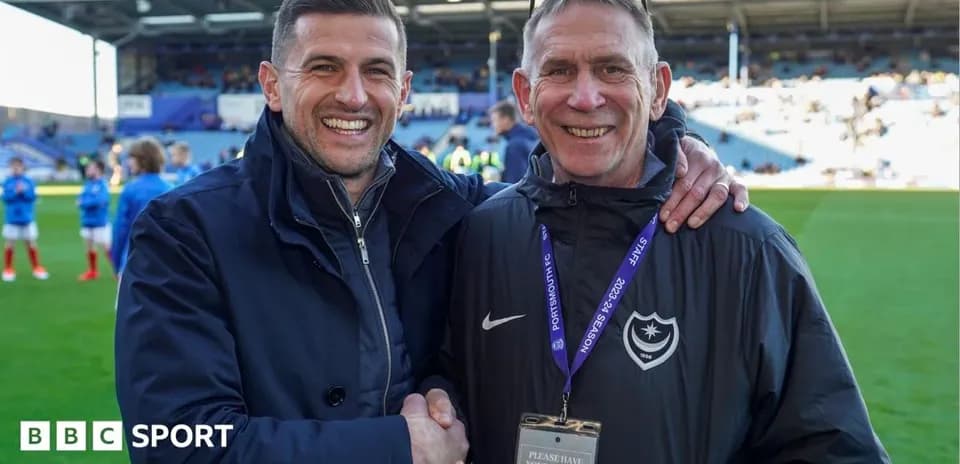 Two men smiling and shaking hands on the pitch