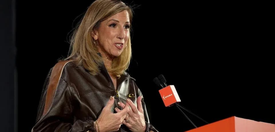 Woman speaking at a podium with WNBA logo