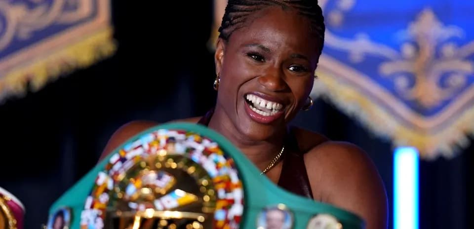Female boxer holding championship belts and smiling