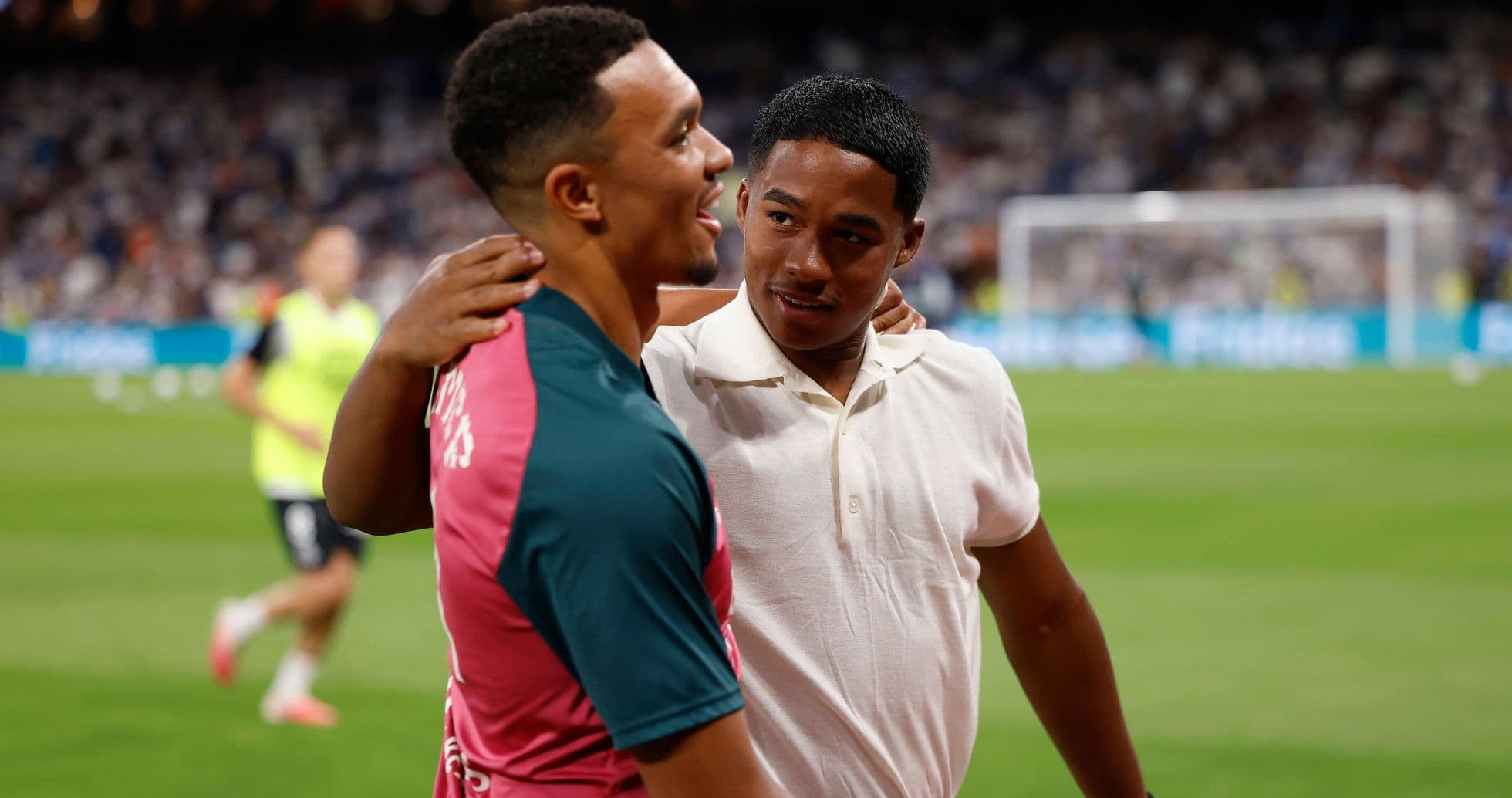 Two players embracing on the pitch after warm-up