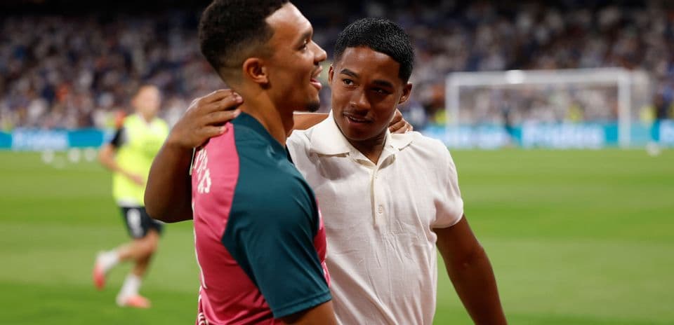 Two players embracing on the pitch after warm-up