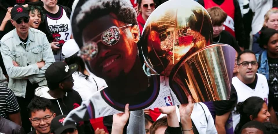 Fans holding a large cutout and trophy at celebration