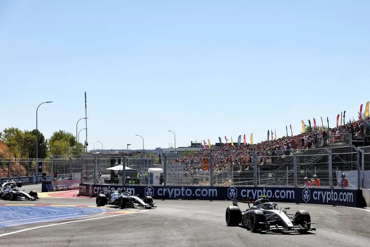 Formula 1 cars racing on circuit with spectators