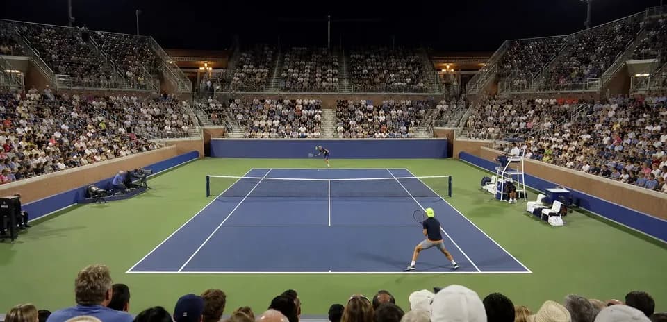 Tennis match with players and large crowd at night