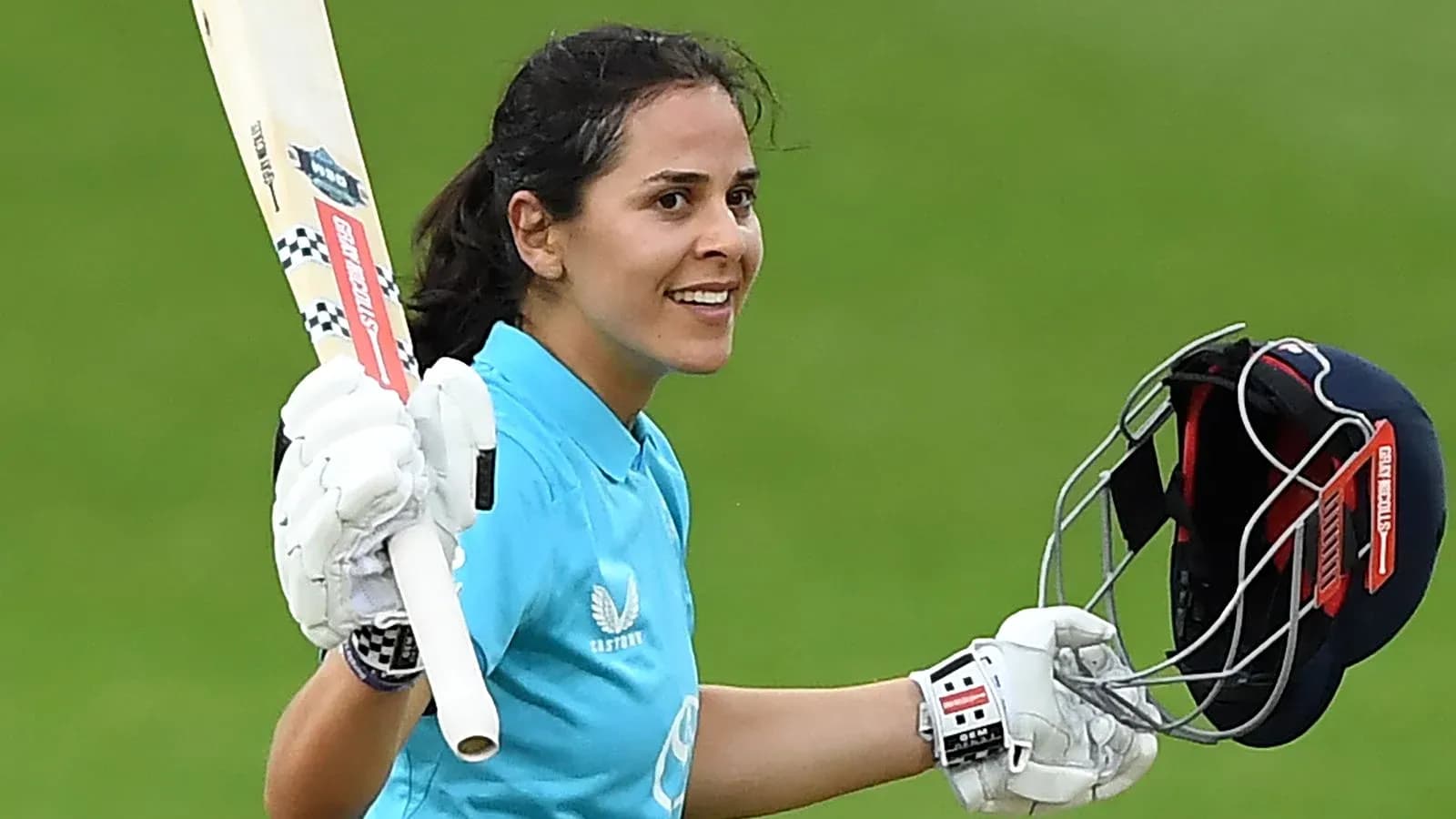 Cricketer celebrating with bat and helmet raised