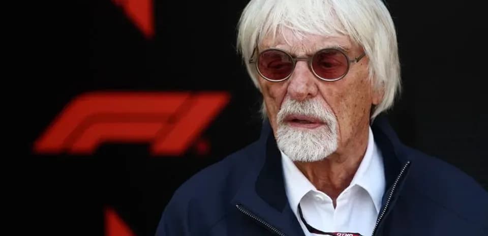 Man with white hair and glasses near F1 logo