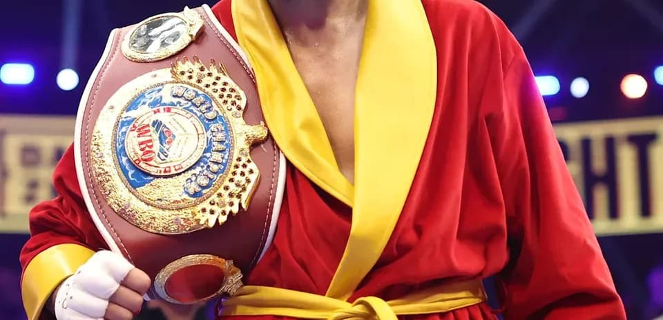 Boxer in red robe holding championship belt