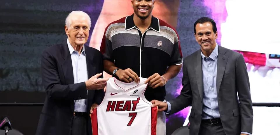 New player holding Miami Heat jersey at press conference