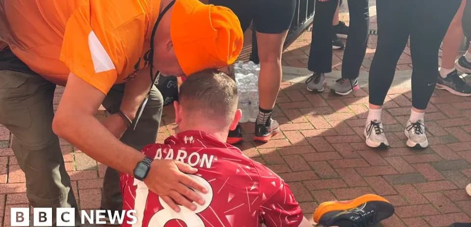 Supporter assisting runner seated on ground