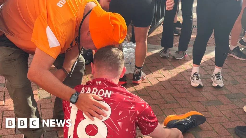 Supporter assisting runner seated on ground