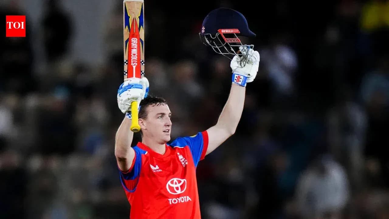 Batter celebrating century with raised bat and helmet