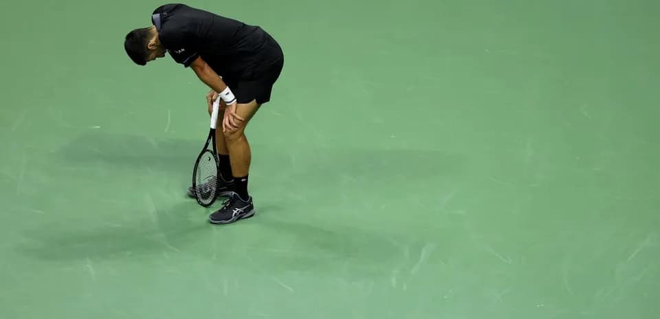 Tennis player bending over holding racket on court