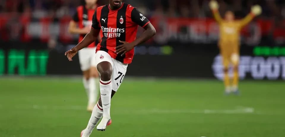 Player in AC Milan kit running with soccer ball